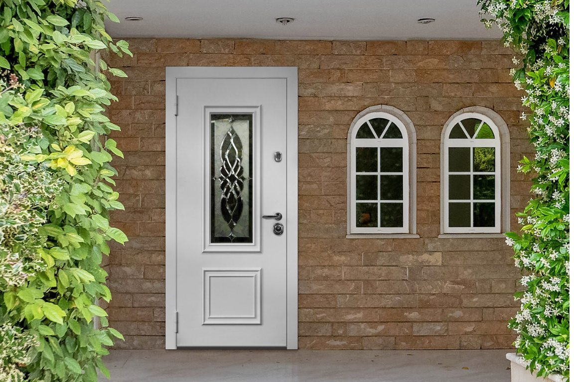 Входные двери в белом оформлении создают современный акцент на фоне каменного фасада и зелени.