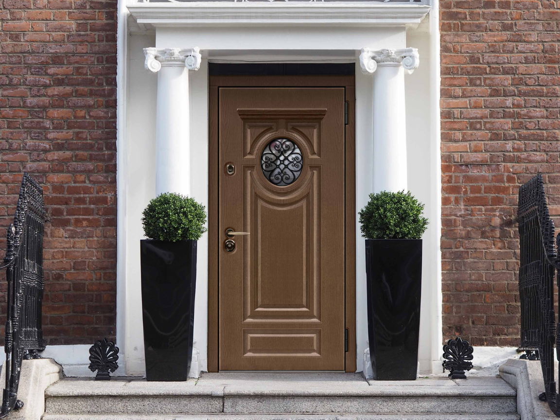 Входная дверь с фрезеровкой в отделке Оак панель с круглым окном и коваными элементами.