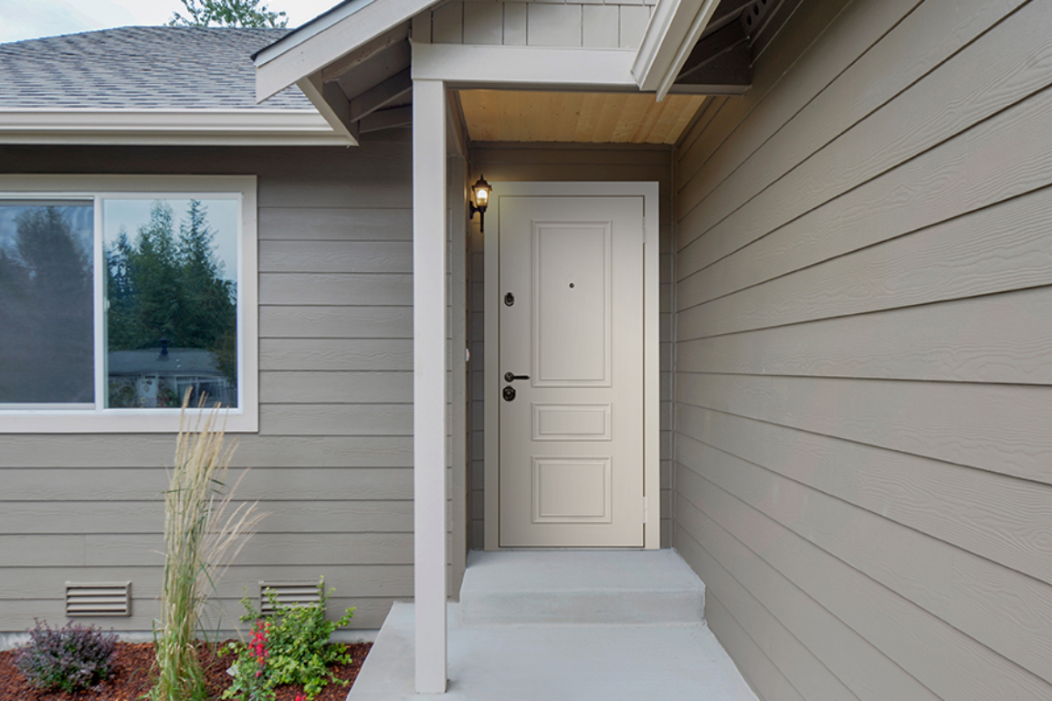 Входные двери с багетами украшают фасад дома, создавая элегантный акцент на фоне крыльца.