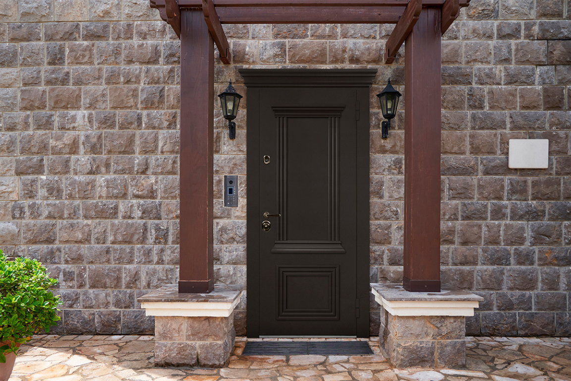 Входные двери с багетами выделяются на фоне каменного фасада и подчёркивают стиль здания.